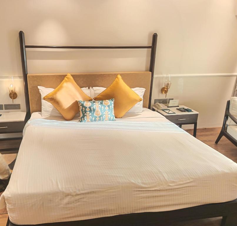 ein Bett mit gelben und blauen Kissen darauf in der Unterkunft Romance Resort Varkala in Varkala