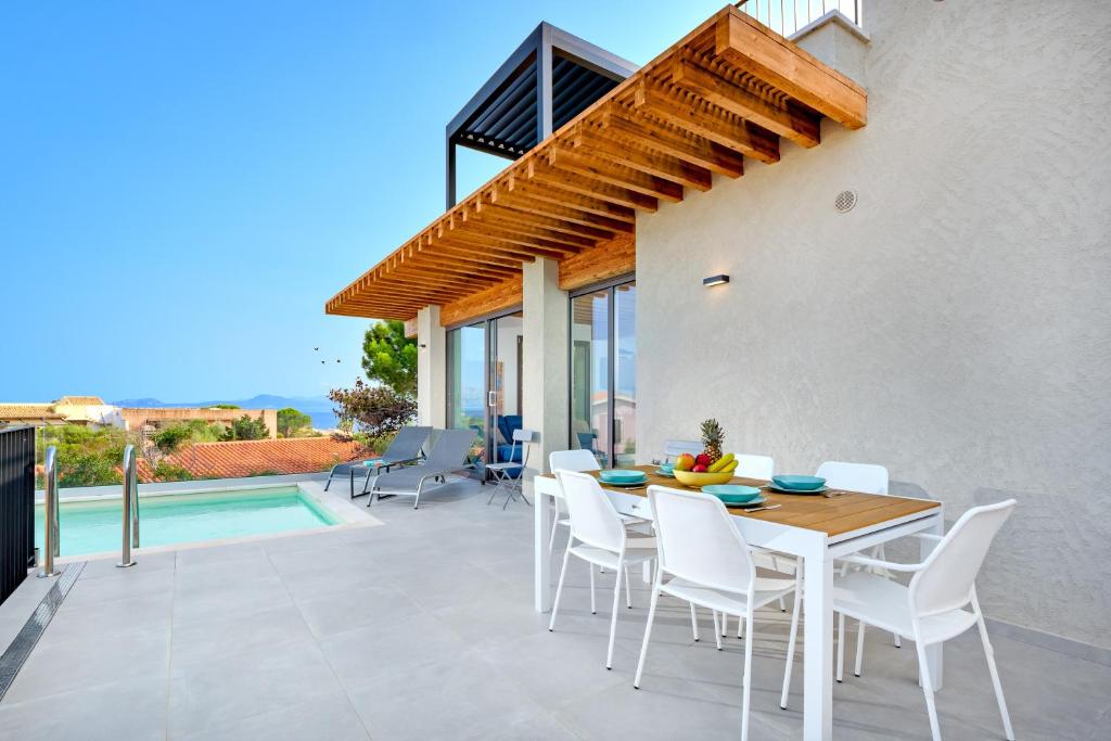 een terras met een tafel en stoelen en een zwembad bij Villa Mathis - by And service in Casa Tamponi