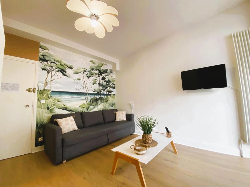 un salon avec un canapé et une télévision sur un mur dans l'établissement Cosy Break Jardins des plantes, au Mans