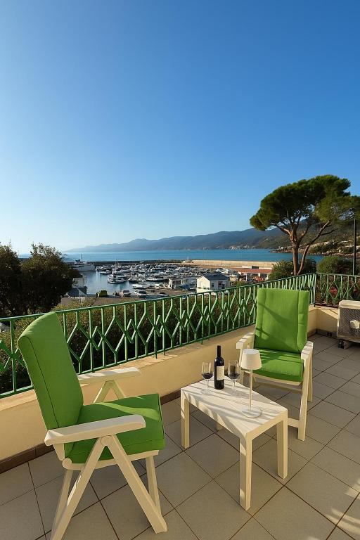 two green chairs and a table on a balcony at Liberty Seaview Apartment Cala Gonone in Cala Gonone