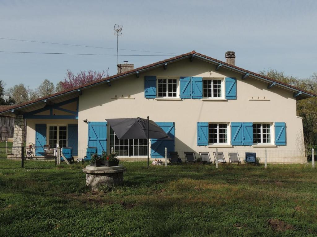 a white house with blue windows and a yard at Gîte du mouta in Saint-Justin