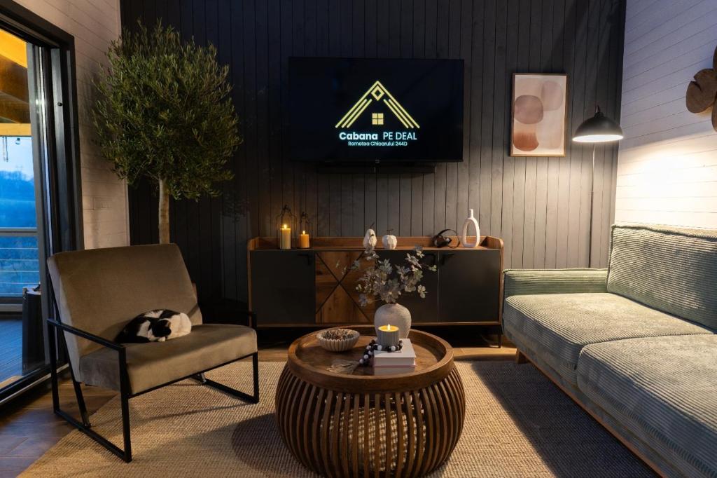 un soggiorno con un divano e una TV a parete di Cabana pe Deal a Remetea Chioarului