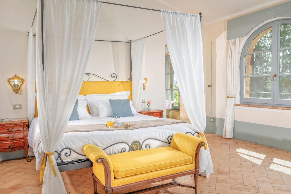 a bedroom with a canopy bed and a yellow chair at Villa MonteLandi in Montalcino