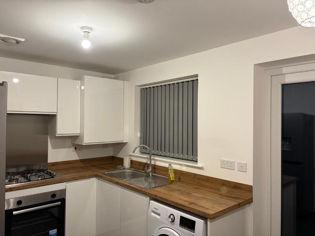 une cuisine avec des armoires blanches et un évier dans l'établissement Bettys Acklam hideout, à Middlesbrough