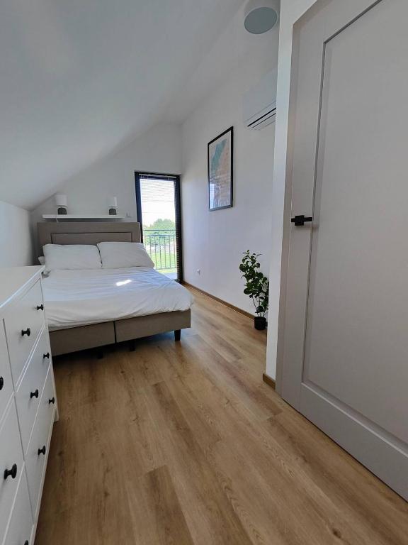 a bedroom with a bed and a wooden floor at Rewal Komfortowy Apartament 2 Sypialnie 10 min od Plaży Parking Taras Grill in Rewal