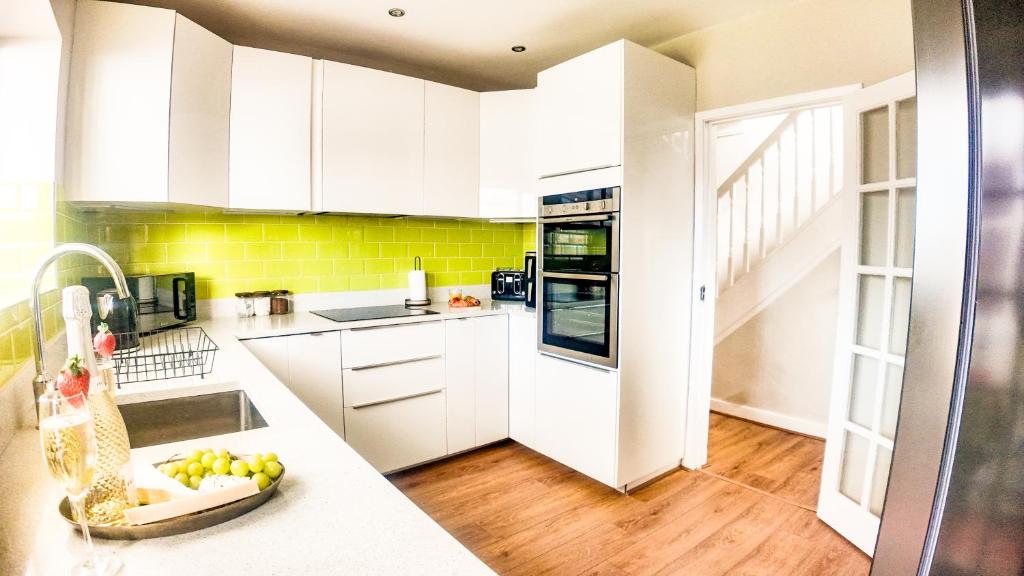 a kitchen with white cabinets and yellow tiles at Stunning 5 Bedroom House in London - Sleeps up to 10 guests - Business - Contractors - Families - Leisure - WiFi - Parking - Garden in Grove Park