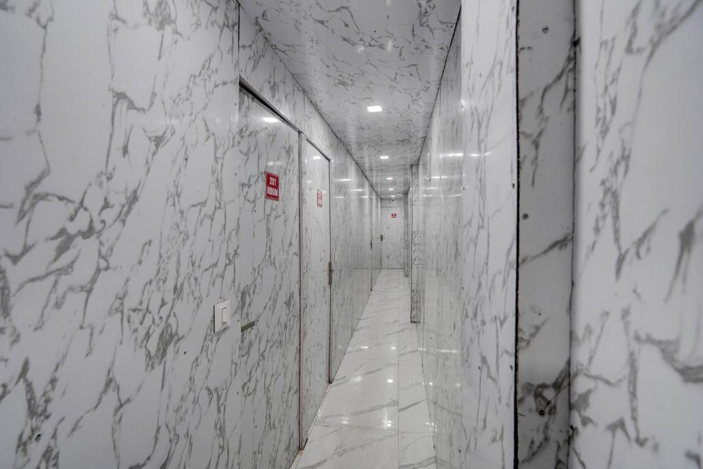 Hotel O POP A Happy Hours Plaza في نيودلهي: ممر بجدران من الرخام الأبيض وممر به لافتة حمراء