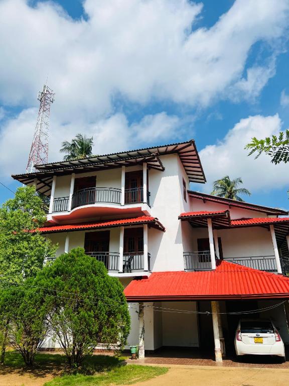 a white building with a red roof at Yala Mangora Inn in Tissamaharama