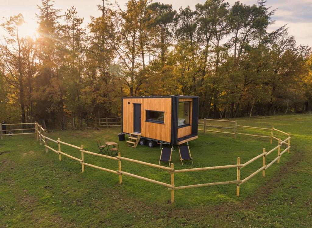 a tiny house in a field next to a fence at Homnest - Refuge en nature au coeur du Tarn in Puybegon