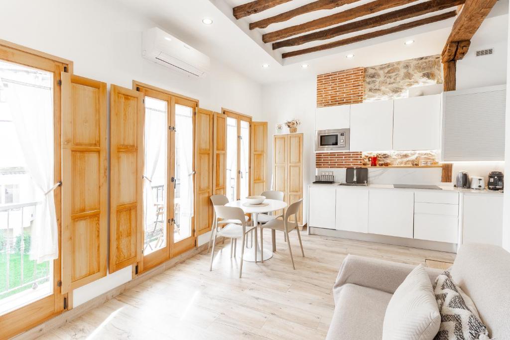 a kitchen and living room with white cabinets and a table at Apartamento en casco histórico con vistas a la iglesia in Castro-Urdiales