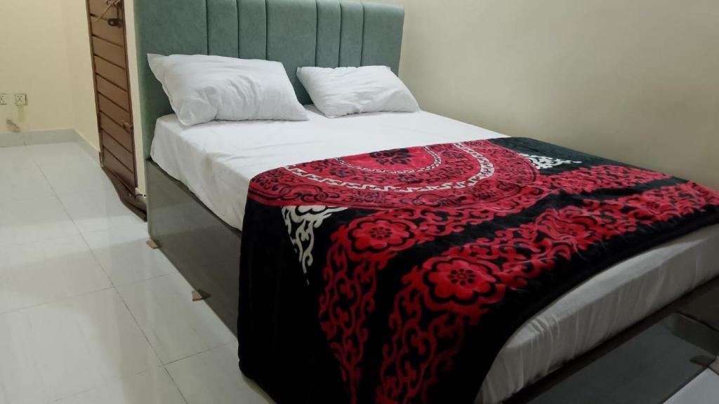 Spacious 2-Bedroom Apartment with Terrace & Multiple Bathrooms في Dargai: سرير عليه بطانية حمراء وسوداء