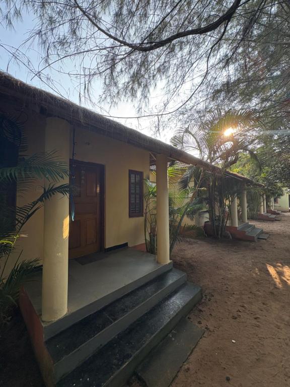 una pequeña casa con porche y puerta en Barefoot and Beyond - Crafted with Kenchas, en Gokarna