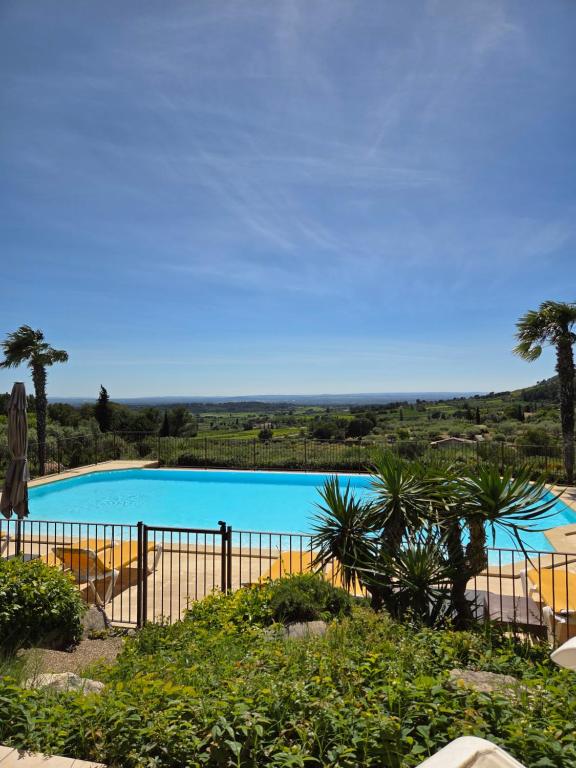 einen Pool mit einem Zaun und Palmen in der Unterkunft Gîte Paradizu, vue imprenable en Provence in Le Barroux