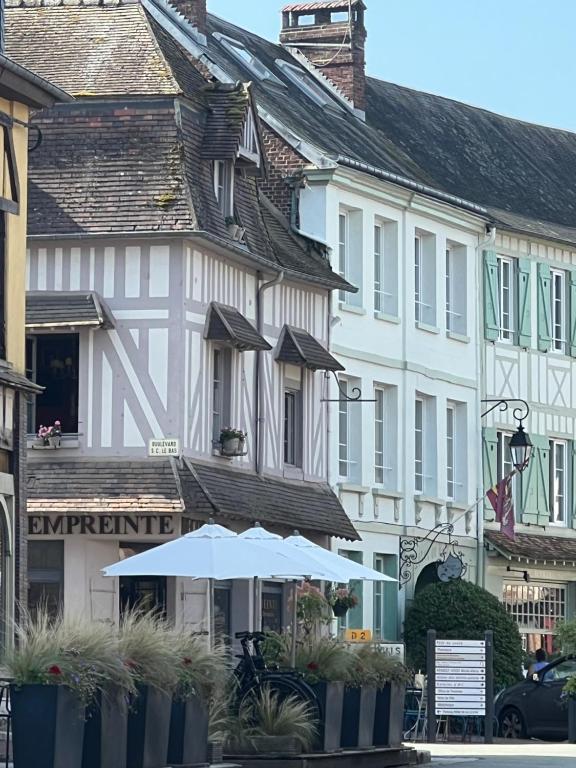 an umbrella in front of a row of buildings at Centre historique de LYONS LA FORET Hotel de Maître le Cottage in Lyons-la-Forêt