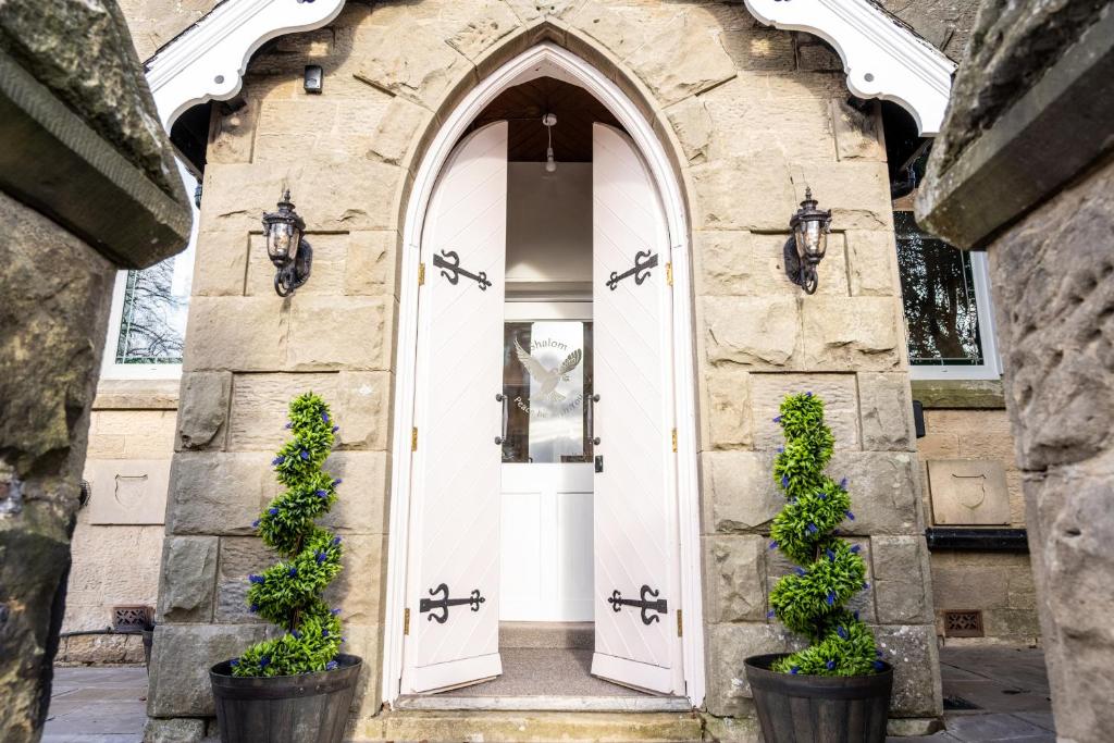 an entrance to a stone building with a white door at Northern Hideaways The Old Chapel, Otterburn in Otterburn