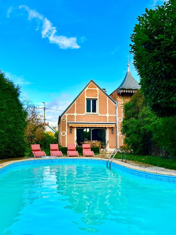 a swimming pool with two chairs and a house at Villa Alexandre III in Dijon