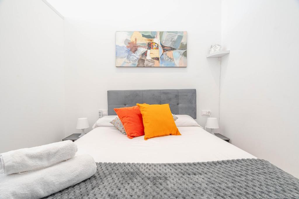 een slaapkamer met een wit bed en 2 oranje kussens bij VLC Suite Yako in Valencia