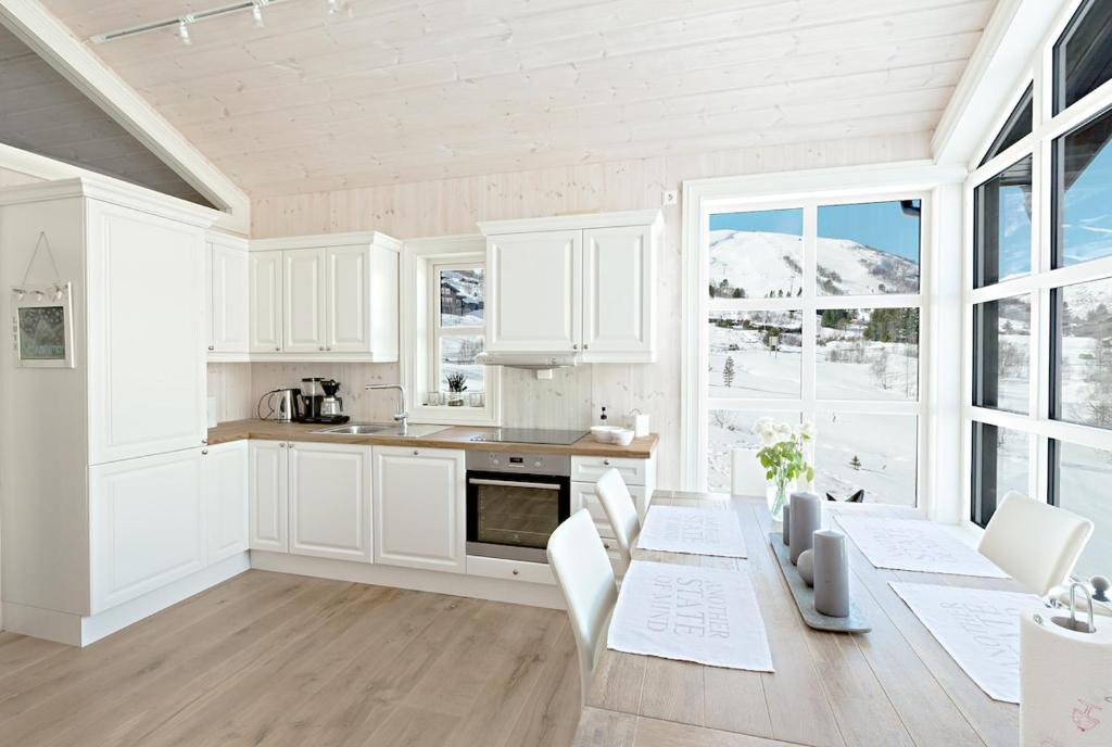 une cuisine avec des armoires blanches et une table avec des chaises dans l'établissement Stranda Fjellgrend 3 bedrooms - 98B, à Stranda