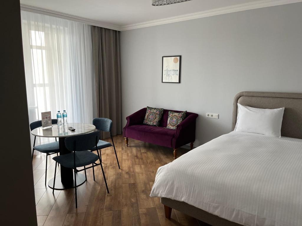 阿斯塔纳71 East Hotel的一间卧室，里面有一张床、一张桌子和一把椅子