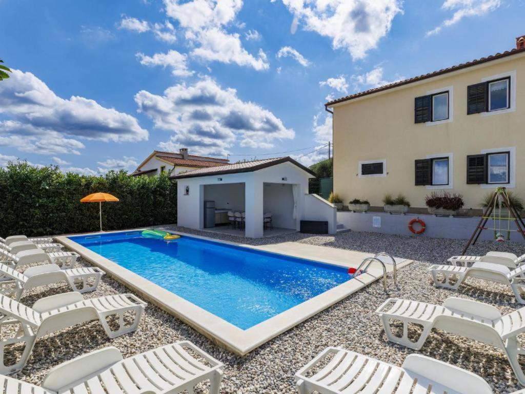 a swimming pool with chairs and a house at Casa Jurican in Višnjan