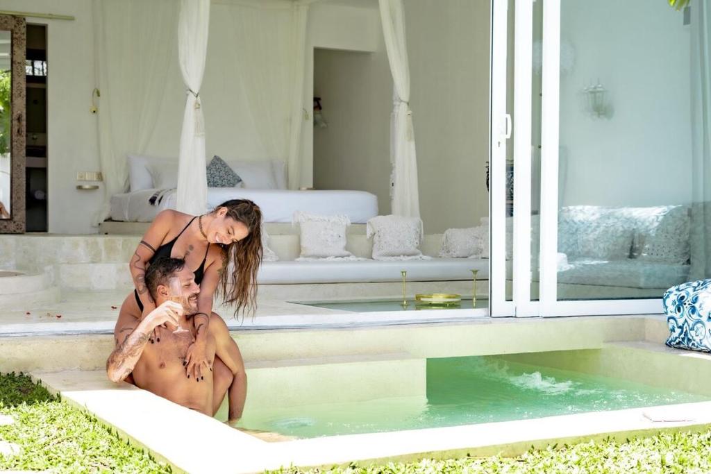 two people sitting in the water in a swimming pool at Marghe 1BR Romantic Villa, 5 Mins to Thomas Beach in Badung