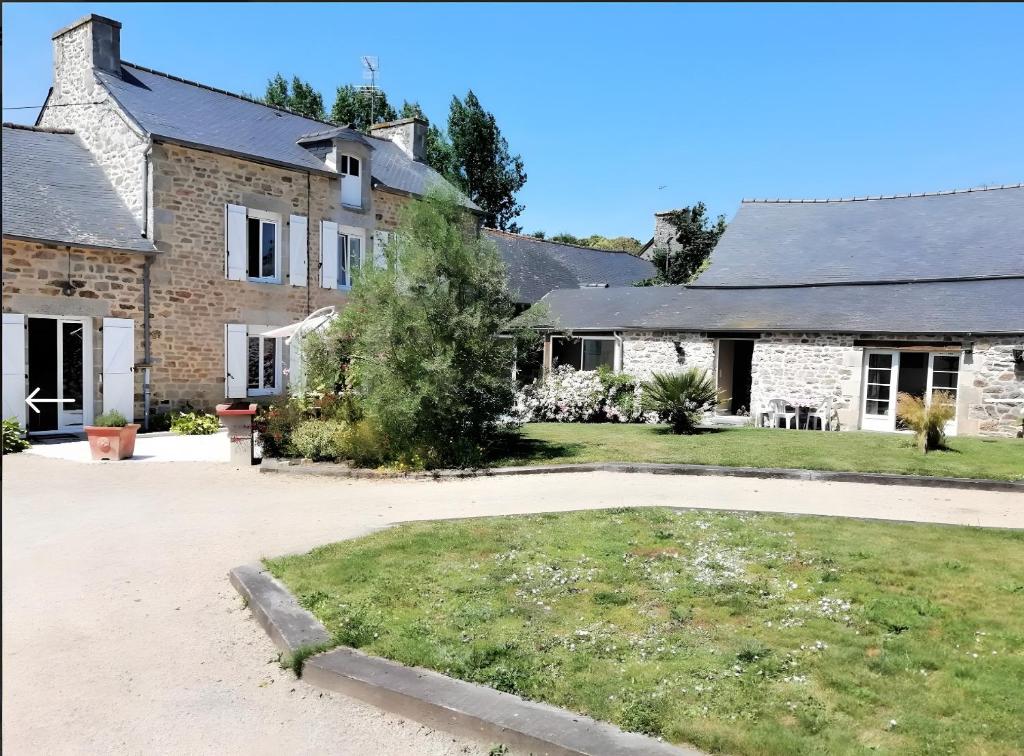 une grande maison en briques avec une cour devant elle dans l'établissement Chambre Grany - Chambre, à Aucaleuc