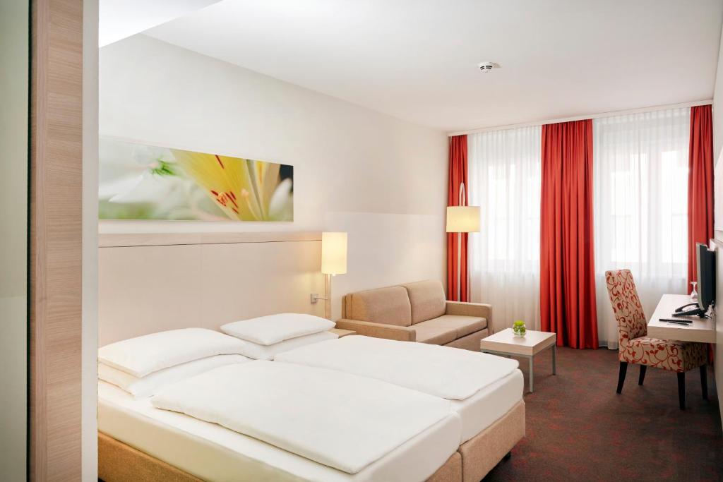 a hotel room with a bed and a desk at H+ Hotel München in Munich