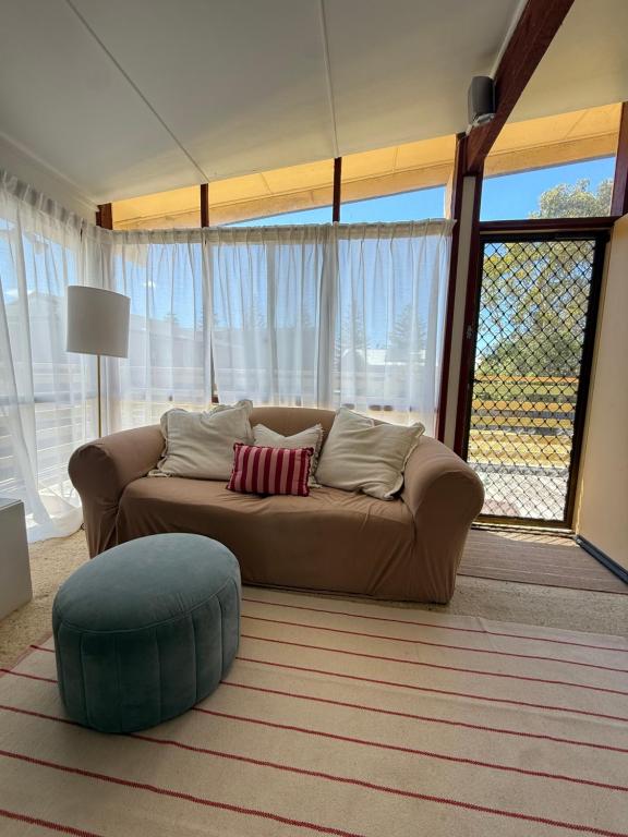 a living room with a couch and a large window at Marlins Beach Shack Broulee in Broulee