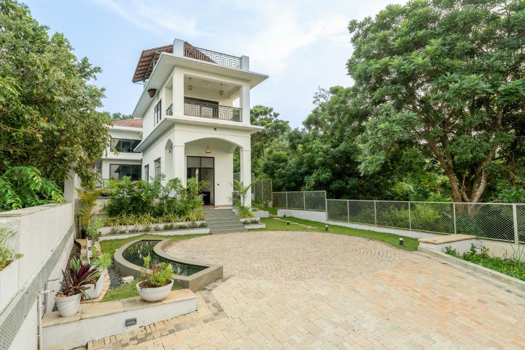a large white house with a large patio at SaffronStays Eden Greens in Calangute