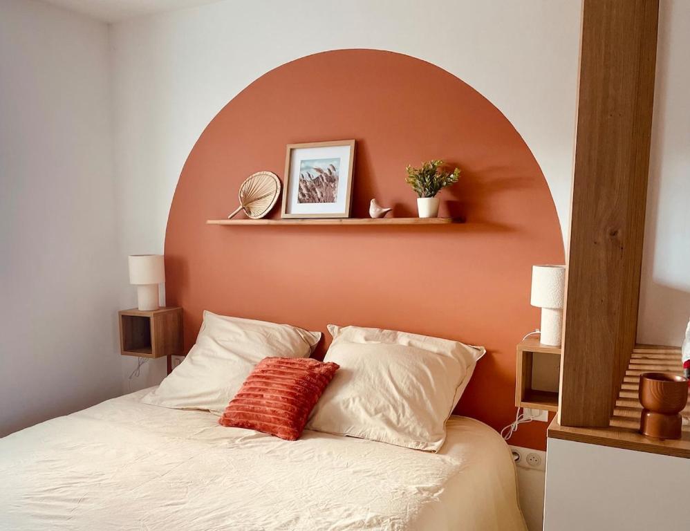 ein Schlafzimmer mit einem Bett mit einer orangefarbenen Wand in der Unterkunft Le Cocon des rêves studio neuf avec terrasse et Parking in Wintzenheim