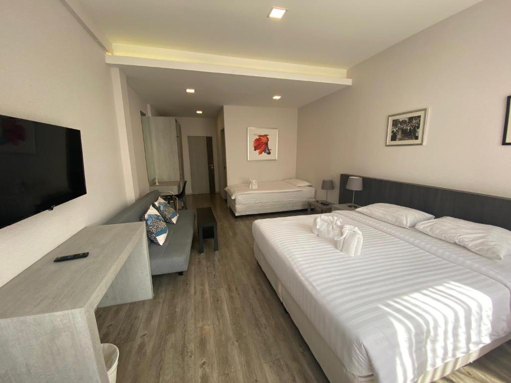 una habitación de hotel con dos camas y un televisor de pantalla plana en Ratchadamnoen Residence, en Bangkok