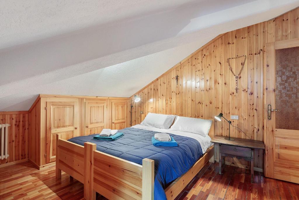 - une chambre avec un grand lit et des murs en bois dans l'établissement Da Gigi e Laura, à Cogne