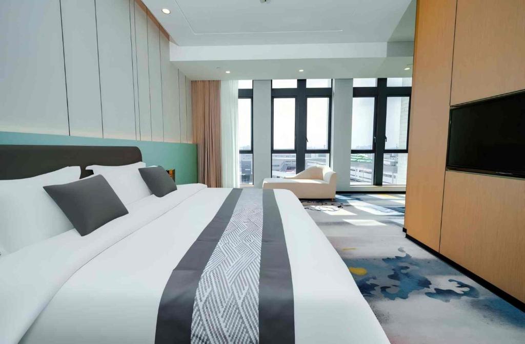 ein Schlafzimmer mit großem Bett und Flachbildfernseher in der Unterkunft Wanlin International Hotel in Foshan