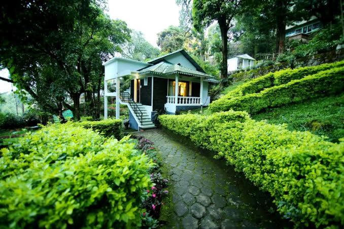 une petite maison sur une colline avec un chemin menant à dans l'établissement Great Escapes Resorts, à Chinnakanal