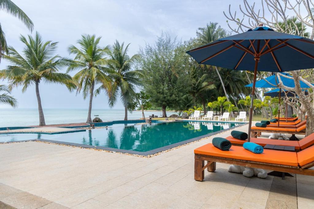 a pool at a resort with an umbrella and lounge chairs at Garto Beach Resort Samui in Ban Thong Phlu