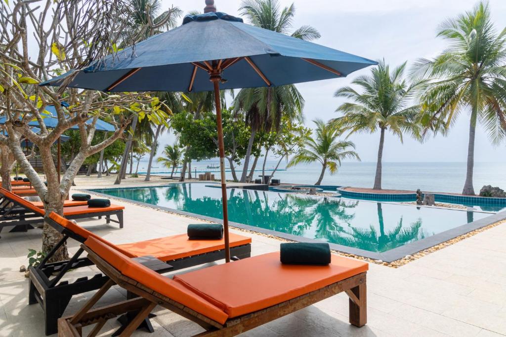 a table with an umbrella next to a swimming pool at Garto Beach Resort Samui in Ban Bang Po