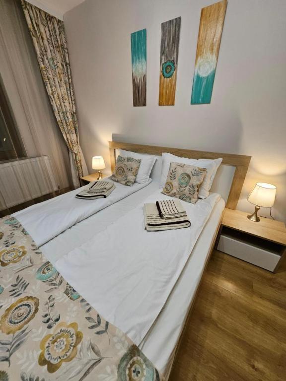 a bedroom with two beds and two tables with lamps at Апартамент Радост in Bansko