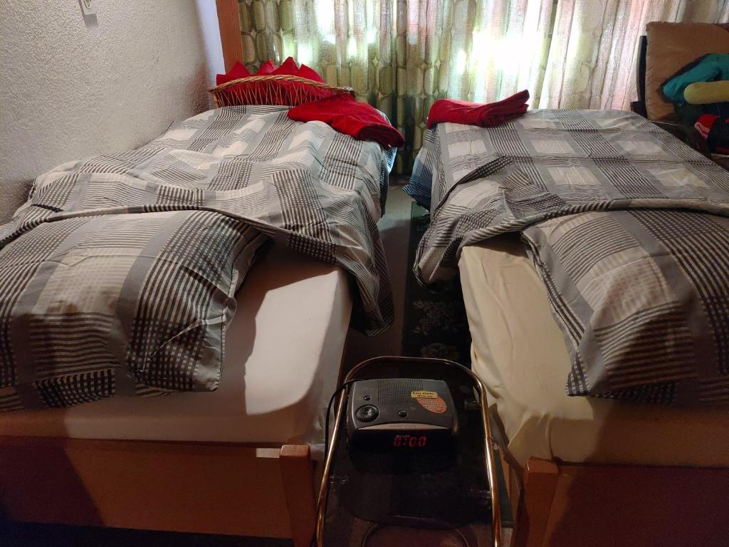 two beds in a bedroom with a clock on the floor at Studio avec vue splendide sur les Diablerets in Les Diablerets