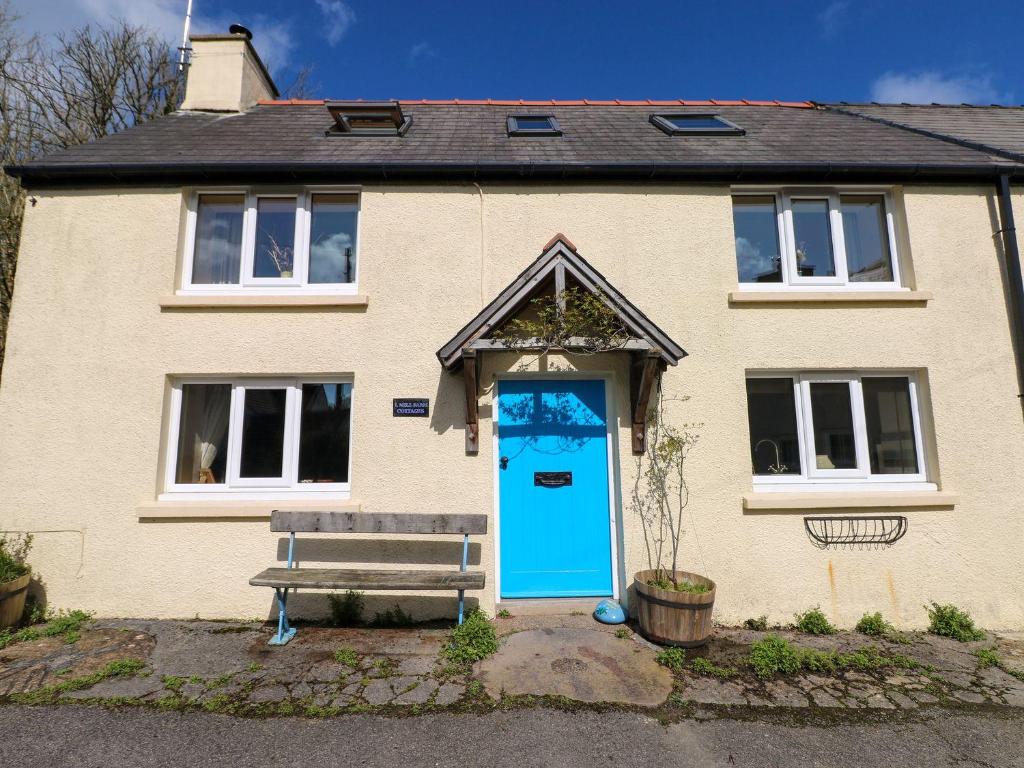 a house with a blue door and a bench at 1 Mill Farm Cottages in Narberth