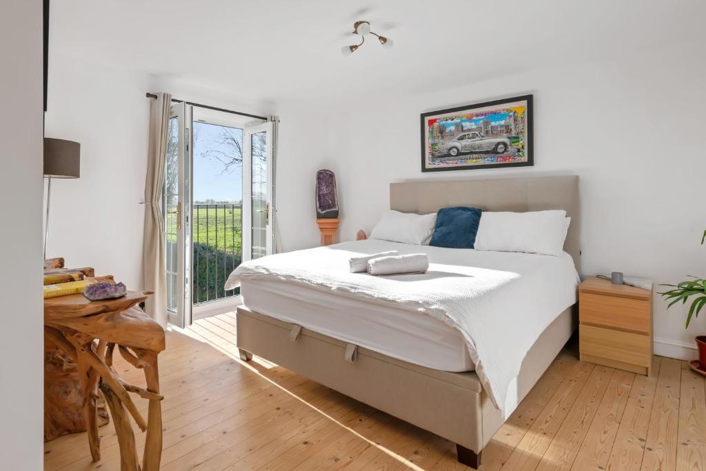 a bedroom with a large bed and a balcony at Spacious 6-Bed Countryside Home Surrounded by Nature in Sutton Bridge