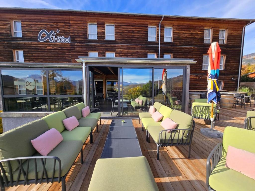 a patio with couches and chairs on a deck at Ax Hôtel Spa & Restaurant in Chorges