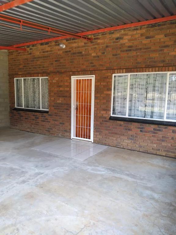 a garage with a brick wall and a red door at The Pasture Loft in Mokopane