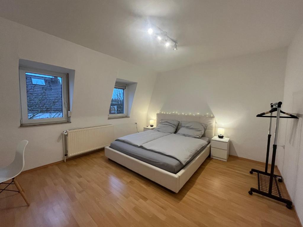 a bedroom with a bed and two windows and a desk at Apartment Airport Dortmund in Holzwickede