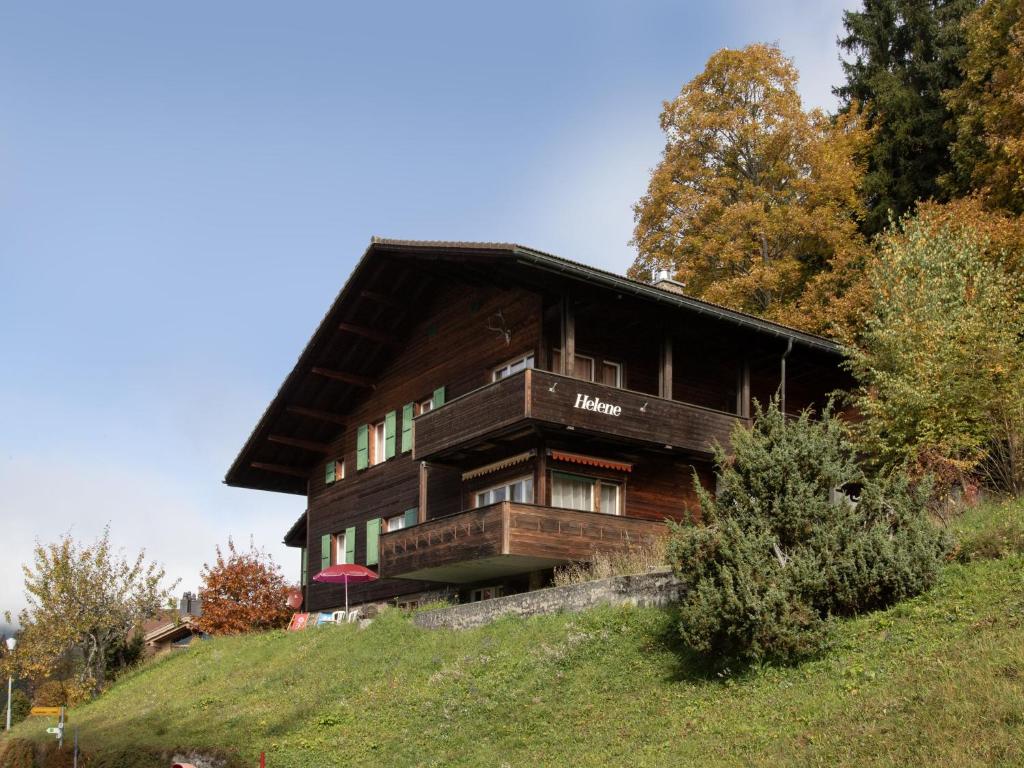 a large wooden house on a hill with trees at Apartment Helene Apt- Hella by Interhome in Wengen