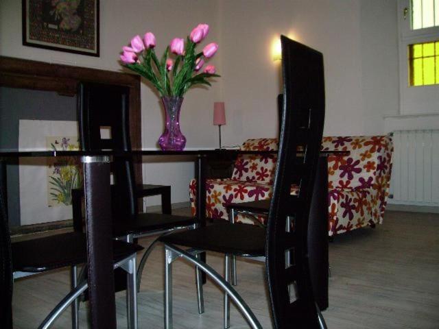 ein Wohnzimmer mit einem Tisch mit einer Vase mit rosa Blumen in der Unterkunft Ferienwohnung für 2 Personen  2 Kinder ca 55 m in Miasino, Piemont Ortasee in Miasino