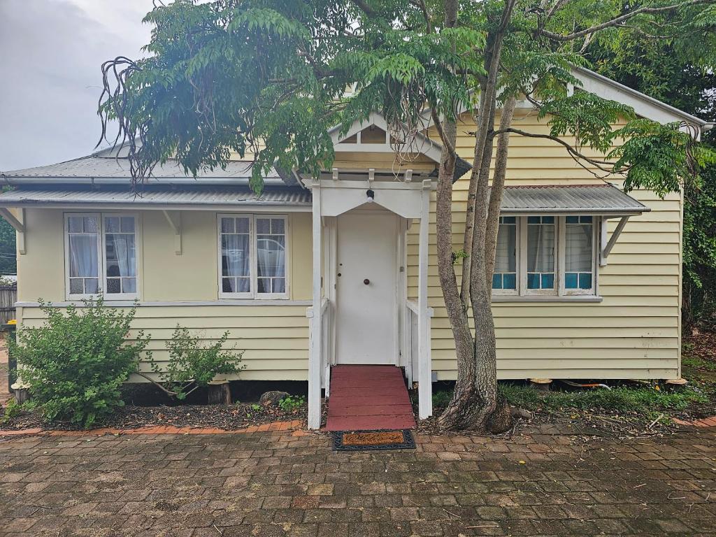 谭伯连山Main St Heritage Charm & Walk to Restaurants的黄色的房子,有白色的门和一棵树