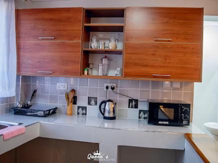 una cucina con mobili in legno e un piano di lavoro di Queen's Premier Suites in Eldoret opposite Tamasha a Kisumu