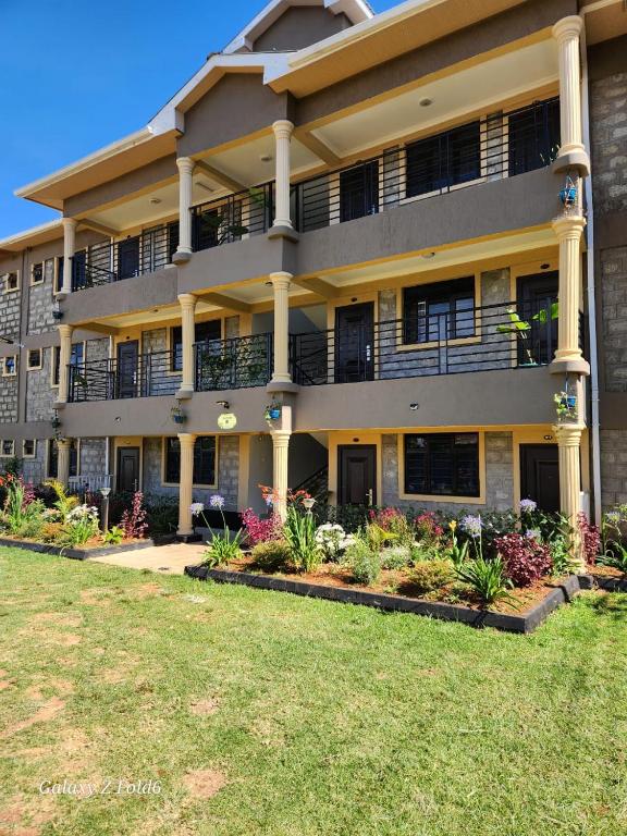 an apartment building with flowers in front of it at Queen's Premier Suites in Eldoret opposite Tamasha in Kisumu