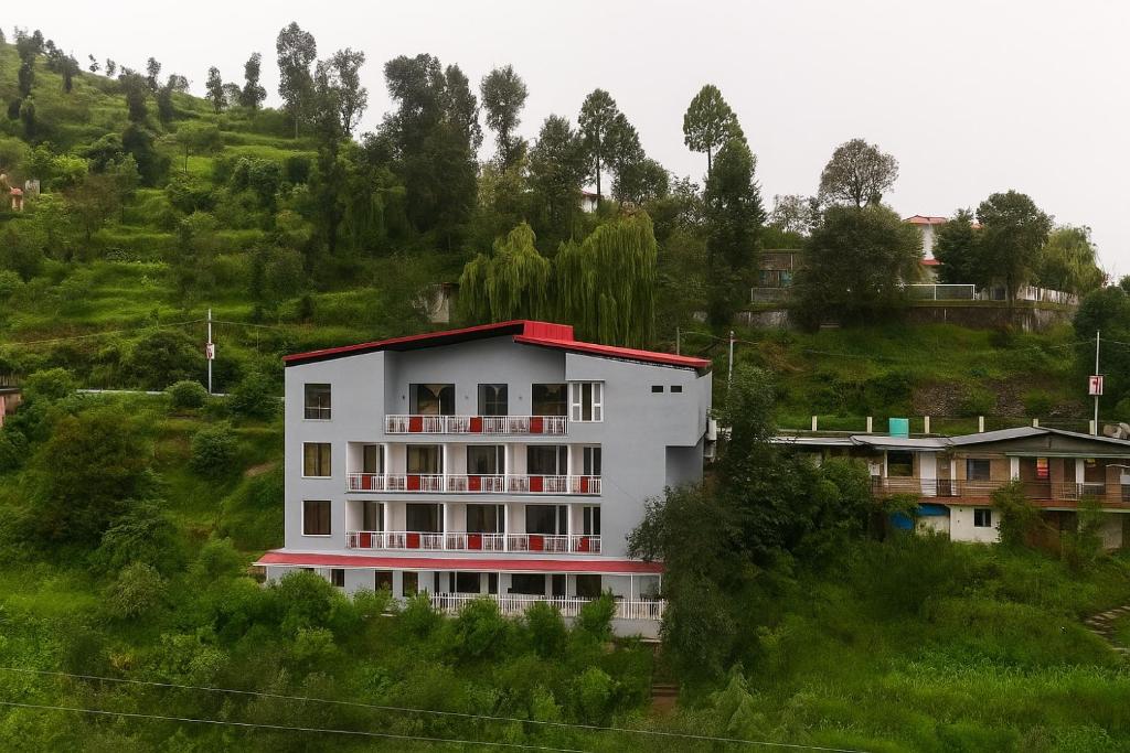 un edificio bianco con tetto rosso su una collina di Kafal Pako Resort - Luxury Mountain View Stay in Mukteshwar a Mukteshwar