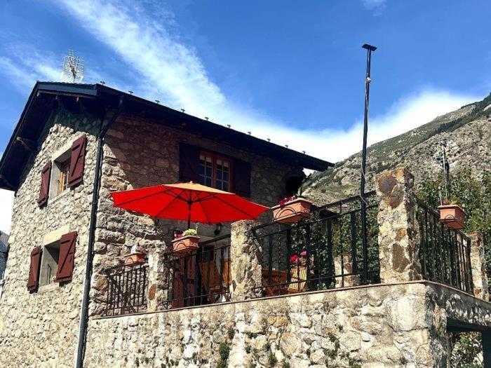 un ombrello rosso sul balcone di un edificio di Escapada con encanto cerca de Porte-Puymorens y Andorra a Porta